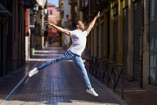 Happy black guy doing an acrobatic jump in the middle of the street. Cuban man.