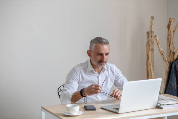 istock Man holding glasses looking at laptop 1397549811