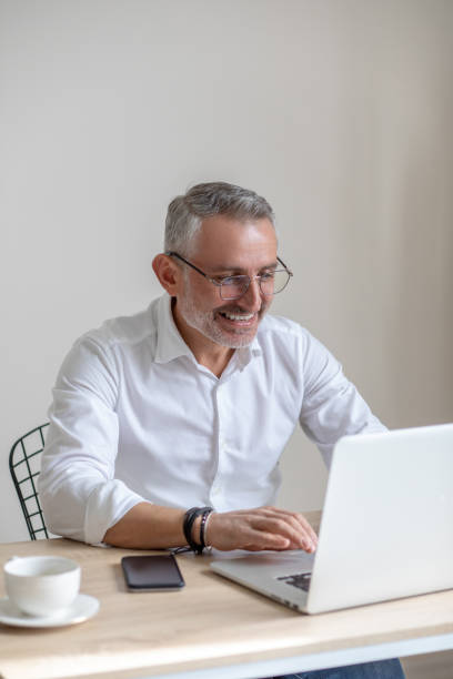 istock Smiling man in glasses typing on laptop 1397549813
