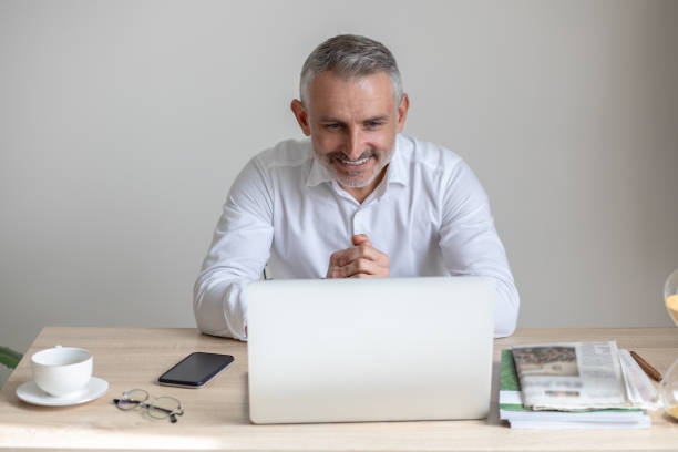 istock Cheerful man looking at laptop sitting at table 1397549822