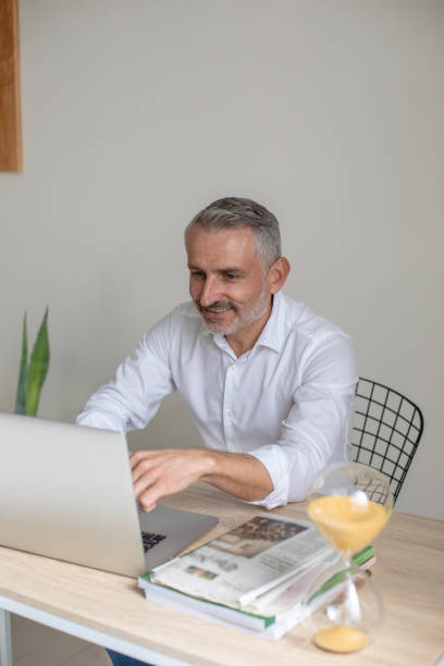 istock Smiling man looking at laptop sitting in office 1397549872