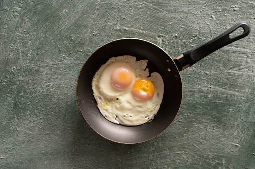 Ugly fried eggs in a frying pan, top view