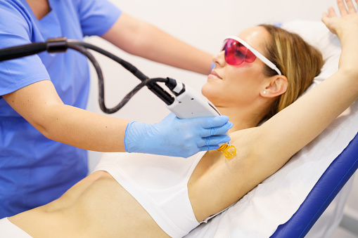 Woman receiving underarm laser hair removal at a beauty center. Laser depilation treatment in an aesthetic clinic.