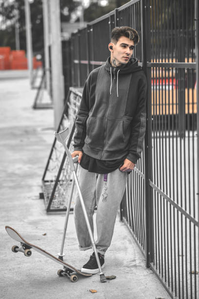 istock Guy on crutches standing near skateboard in park 1397554330