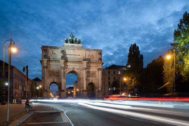 illuminated Victory Gate in Munich at blue hour long exposure of illuminated Victory Gate in Munich with light lines  of traffic at blue hour siegestor stock pictures, royalty-free photos & images