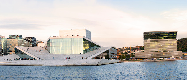 Oslo, Norway - 09/04/2021: Scenic Night Evening View Of Illuminated Norwegian National Opera And Ballet House Among Contemporary High-Rise Buildings. Panorama, Panoramic View.