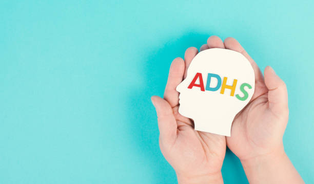 istock Hands holding a head with the german word ADHS which means attention deficit hyperactivity disorder, ADHD symptom, mental health 1397561453