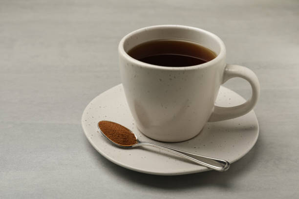 istock Cup of delicious chicory drink and spoon with powder on light grey table 1397565556