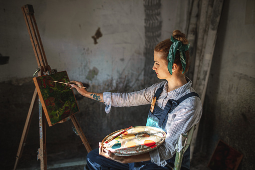 Young Caucasian woman painting in her home art studio