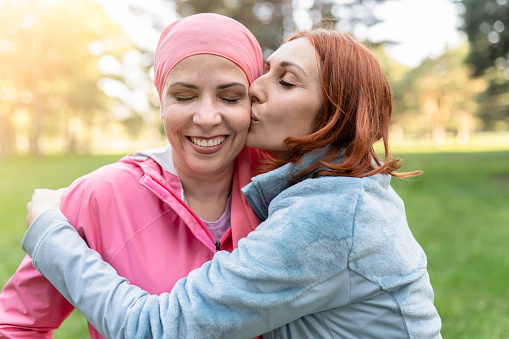 mujeres abrazadas con los ojos cerrados mientras besan al luchador contra el cáncer - concepto lucha contra el cáncer de mama - photo