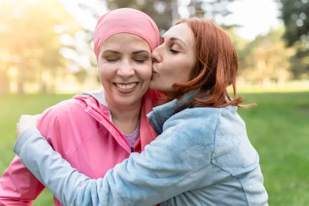 Photo of women hugging with closed eyes while kissing the fighter against cancer - concept fight against breast cancer -