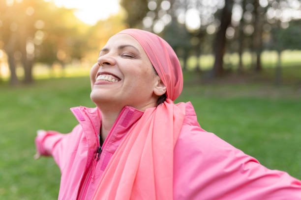 donna matura felice che sorride con una sciarpa rosa, simbolo contro il cancro al seno, - concetto positivo di combattente contro il cancro - - patient female hospital recovery foto e immagini stock