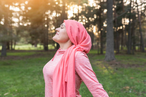 woman with cancer in nature while breathing fresh air, concept of a woman fighting cancer, woman with pink scarf relaxed. woman with cancer in nature while breathing fresh air, concept of a woman fighting cancer, woman with pink scarf relaxed. brest cancer hope stock pictures, royalty-free photos & images