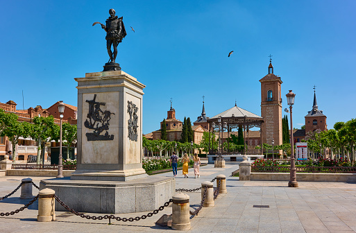 Alcala de Henares, Spain - May 13, 2022. Plaza de Cervantes square, with the Miguel de Cervantes statue in the foreground. Alcala de Henares, Region of Madrid, Spain.