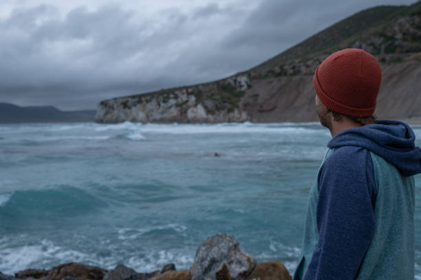 istock Young man walks on a pier, stormy sky 1397570089