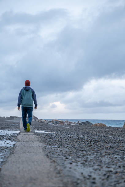 istock Young man walks on a pier, stormy sky 1397570106