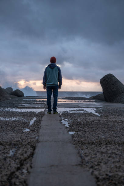 istock Young man walks on a pier, stormy sky 1397570266