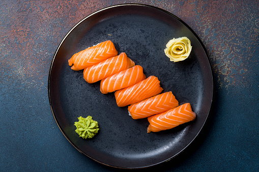 Close up of nigiri sushi with salmon, tuna, prawn in a take away container.\nSake nigiri, majuro nigiri, ebi nigiri.