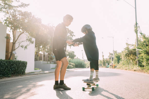 istock Asian father and son skateboarder practicing in the public park. 1397572033