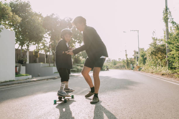 istock Asian father and son skateboarder practicing in the public park. 1397572047