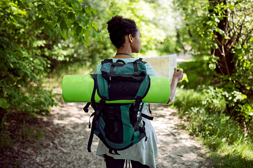 Woman hiker with backpack hiking while holding a map