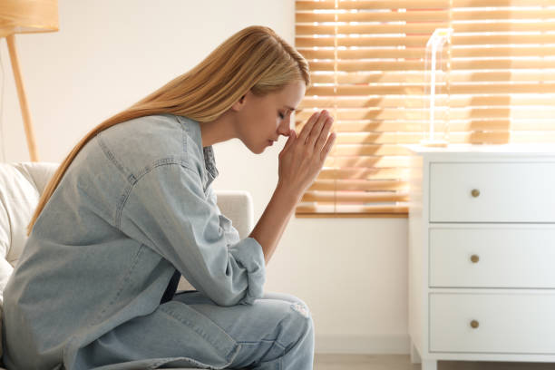 istock Religious young woman with clasped hands praying indoors. Space for text 1397573359