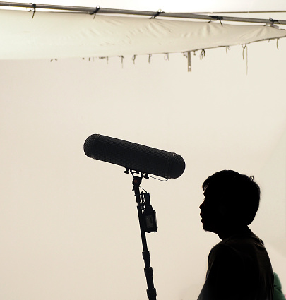 Boom Microphone hold up high by video or film production crew team man and recording sound for movie in a big studio.