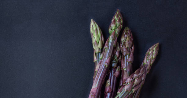 istock Asparagus. Fresh purple asparagus on black slate background. Top view copy space.