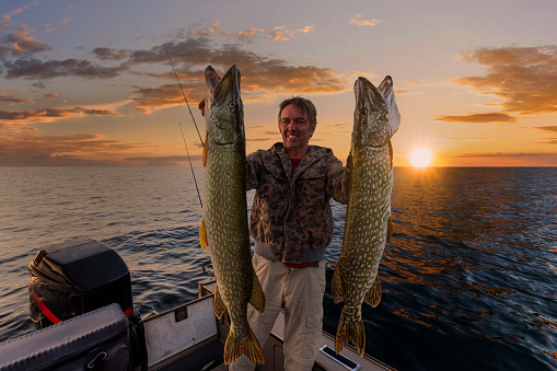 Happy angler with pike fishing trophy