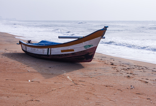 Kannur, India - December 10, 2011: Fisherman prepares to set out on a fishing trip in a small traditional boat along Cherai beach near Thottada village, 10 km south of Kannur, Kerala, India. The shot shows the coconut palms lining the beach along the Malabar coastline.