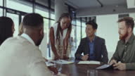 istock Young african american buinesswima talking to her colleagues in a meeting at a table in an office at work. Businesspeople having a meeting planning at a table at work 1397579299