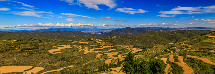 Panoramic view of terraced fields and mountains surrounding a valley by Iglesia de Santa Maria fortress church in Ujue, Navarra, Spain