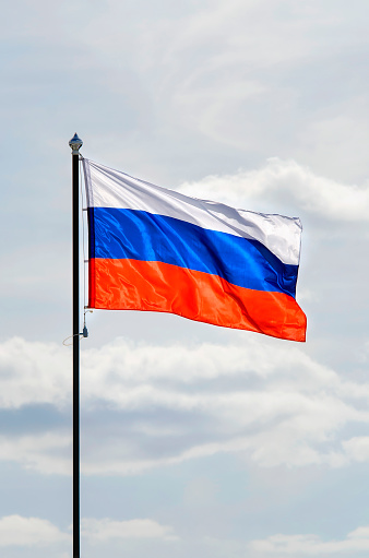La bandera rusa ondea en el viento contra un cielo azul. Fotografía vertical. photo