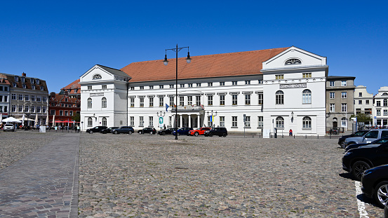Wismar, Germany, May 8, 2021 - The classicist Wismar town hall on the market square and some unidentified people in the background