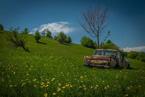 Very old broken car on spring color meadow near Banska Stiavnica town in sunny day