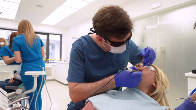Male dentist performing descaling procedure on a female patient