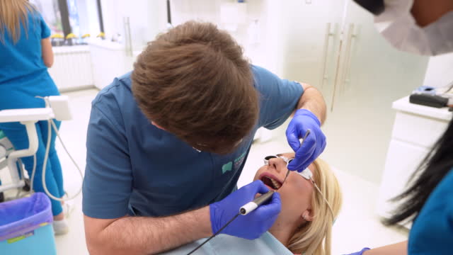 Male dentist performing descaling procedure on a female patient