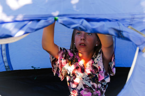 メッシュの防蚊窓の後ろにあるキャンプ用の青いテントの中に快適に座って、外を見ている少女。肖像画十代の女の子。朝。ウィンドウを開く/閉じます。旅行の子供。青いテント。焦点が合 - netting child mosquito netting window ストックフォトと画像