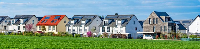 Terraced houses and semi-detached houses on the edge of a field in a new housing estate in a suburb of Frankfurt am Main in sunny weather