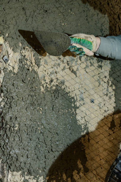 istock A man throws concrete mortar on the wall, the first layer of plaster on the wall, repair work in Ukraine. 1397593497