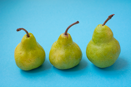 three green pears on a blue background. Healthy fruits