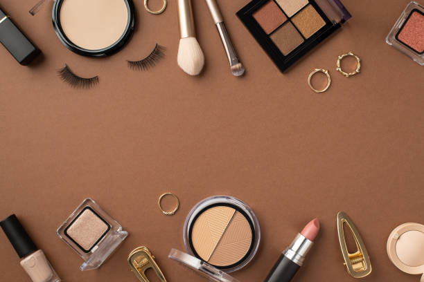 istock Make up concept. Top view photo of lipstick compact powder makeup brushes false eyelashes nail polish blush eyeshadow palette gold rings and barrettes on brown background with copyspace 1397594355