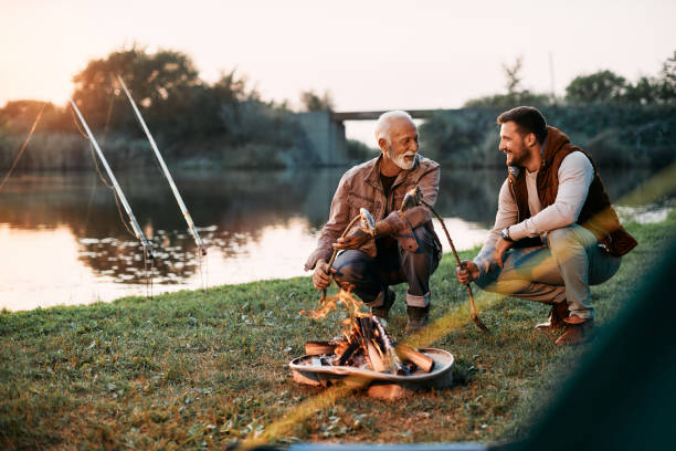 istock Happy senior father and his son enjoying in preparing fish on bonfire while camping at sunset. 1397595458