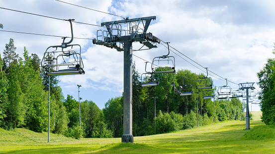 Cable car, ski lift with blue seats in summer among the green pine trees