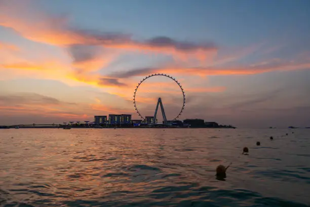 Amazing sunset colors over the sea view to the Ain Dubai, giant Ferris at artificial island Bluewaters Island  close to JBR beach. Dubai Eye fits perfect to modern UAE skyline. Ain Dubai or Dubai Eye, at Bluewaters manmade Island in the United Arab Emirates, is the world’s tallest and largest observation wheel, with a height of over 250 m. The wheel opened on 21 October 2021.