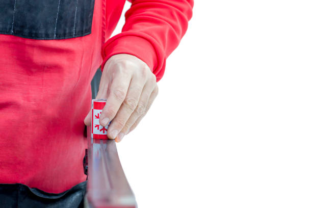 Ski preparation service technician applies ski grip ointment for classic ski ride on white background