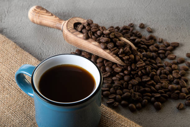 Blue cup of coffee with coffee beans on concrete background