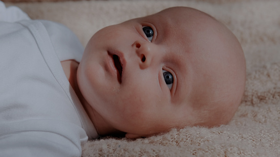 A Cute happy 2 month baby boy lying on bed