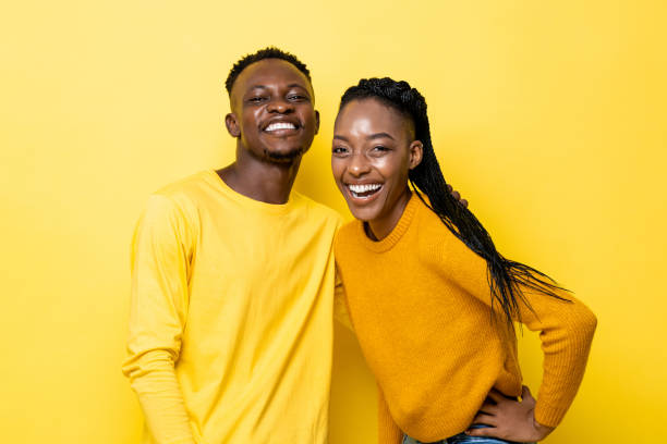 Smiling young African American couple in yellow isolated studio background stock photo