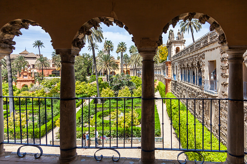 Seville, Spain - 8th April 2022, The view looking out from one of the balconies of the Real Alcázar, a UNESCO world hertiage site, to the walled garden below where some people are relaxing.